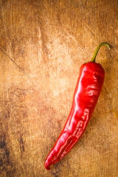 Red hot chili peppers on old wooden table surface texture background