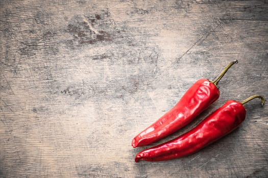 Red hot chili peppers on old wooden table surface texture background