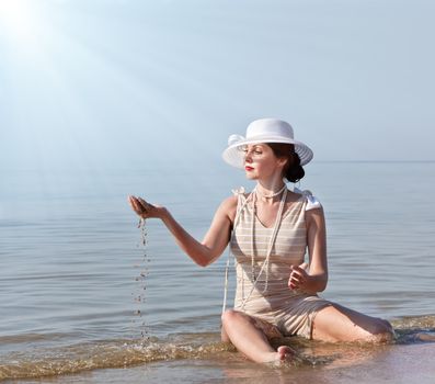 Woman in bathing suit and white hat against the sea