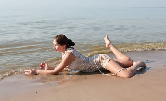 Woman in a striped retro bathing suit lying in water on beach