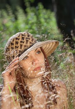 Young woman in a hat on natural background with gras
