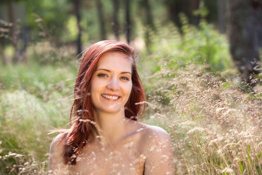 Young woman in the grass on natural background in the sunlight