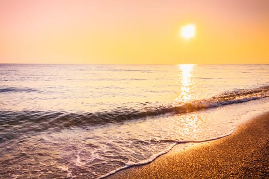 Soft sea ocean waves wash over golden sand background. Sunset, sunrise, sun