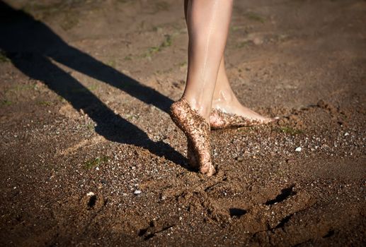 Girl's barefoot legs on the sand beach