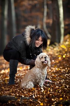 Girl and cocker spaniel in the autumn forest. Focus mainly on the dog