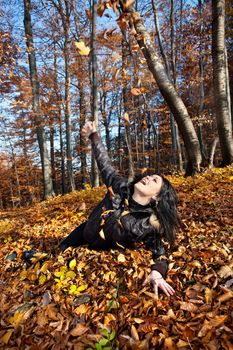 Young woman lying in fallen autumn leaves