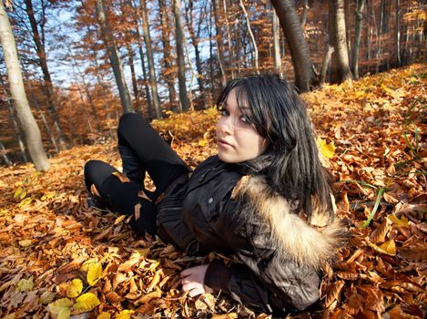 Young woman lying in fallen autumn leaves