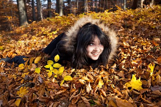 Young woman lying in fallen autumn leaves