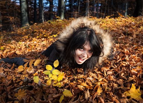 Young woman lying in fallen autumn leaves