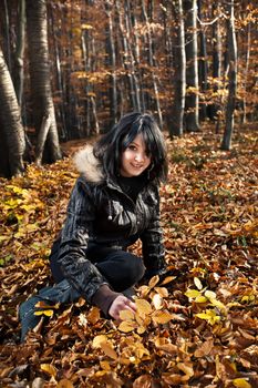 young woman sitting on autumn leaves