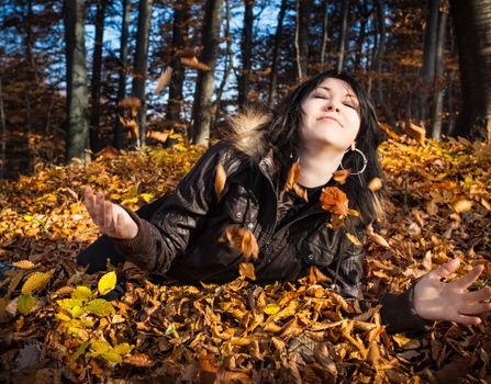 Young woman lying in fallen autumn leaves