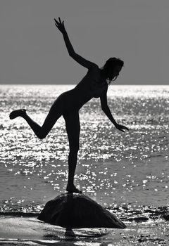 Silhouette of a naked sexy girl on the sea sunset background