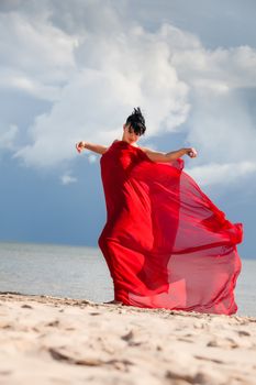 Young naked woman on a beach with red fabric