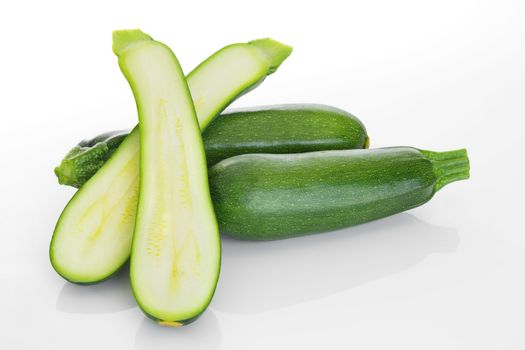 Zucchini on white background, whole and cut in two.