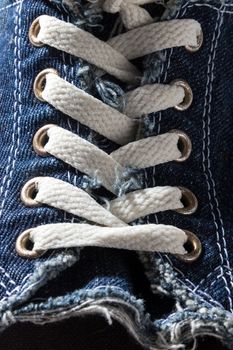 Close-up of a blue denim shoe with laces.