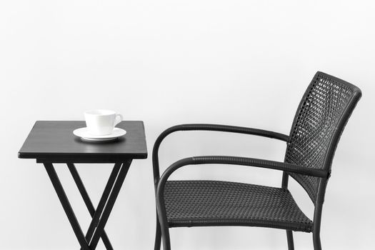 Black chair, table and white cup of tea or coffee.