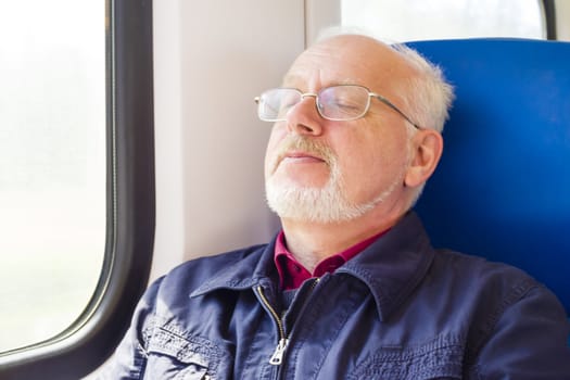 Relaxed old man sitting near the window in the carriage