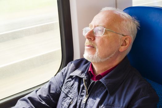 Relaxed old man sitting near the window in the carriage