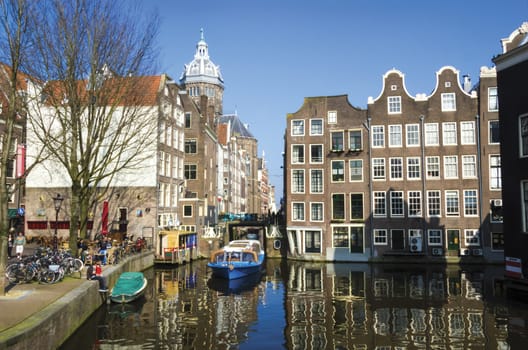 Blue boat on channel in Amsterdam. Typical Amsterdam architecture. Urban space in the spring.