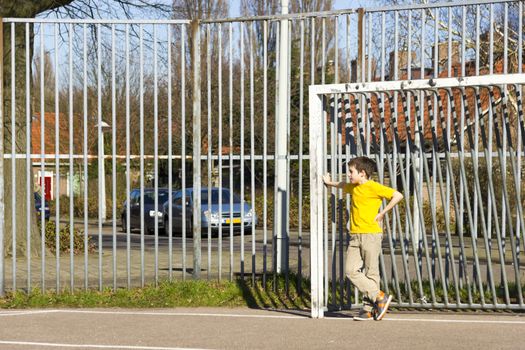 Cute boy staying in gate on the playground