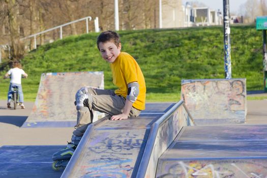 smiling teenage boy in roller-blading protection kit in a skate park