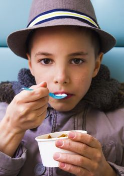 Cute teenage boy eating ice cream with chocolate topping