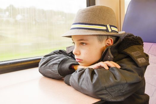 Boy rides on a train and looking out the window.