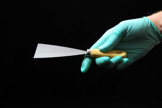 One Spatula and a Hand on a Black Background