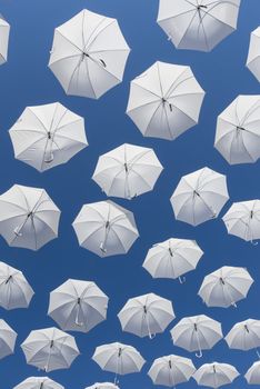Ornamental white umbrellas flying in the blue sky