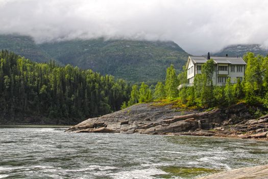 Waterfall and river in green forest in northern Norway at summer