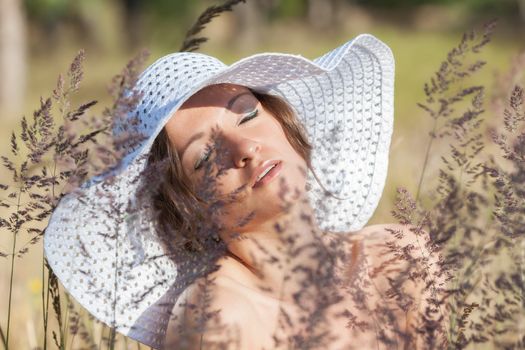 Young woman in white hat on natural background with grass