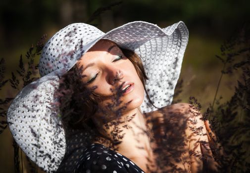 Young woman in white hat on natural background with grass