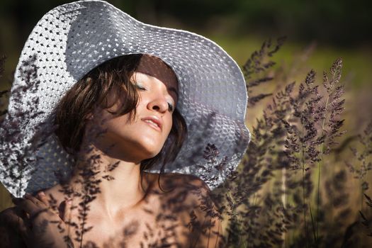 Young woman in white hat on natural background with grass