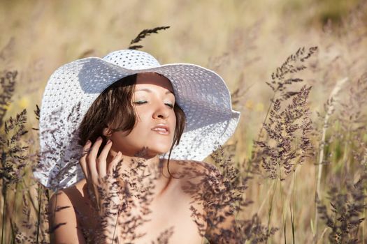 Young woman in white hat on natural background with grass