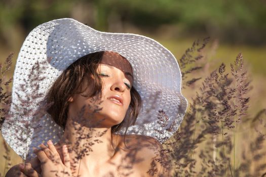 Young woman in white hat on natural background with grass