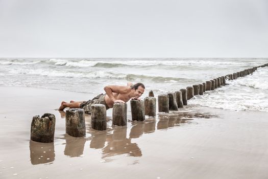 Middle-aged man doing pushups on the beach