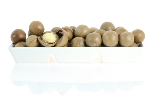 macadamia in  white bowl  on white background with reflection