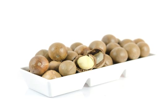 close up macadamia in  white bowl  over  white 