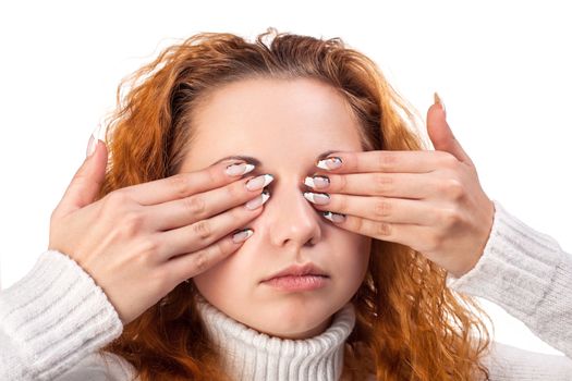 Portrait of red-haired woman covering her eyes by the hands, over white background