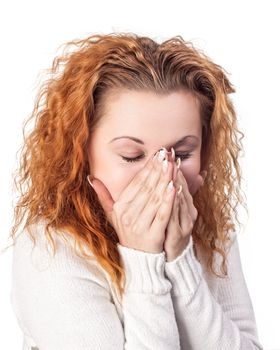 Portrait of red-haired woman covering her face by the hands, over white background