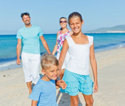 Family of four having fun on tropical beach