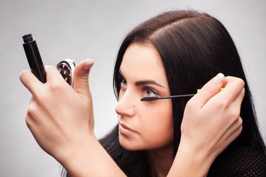 Woman applying mascara on her eyelashes