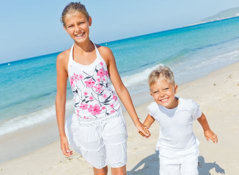 Adorable happy boy and girl running on beach vacation