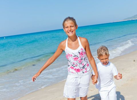 Adorable happy boy and girl running on beach vacation