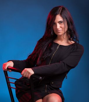 Beautiful young woman sitting on chair. Studio shot