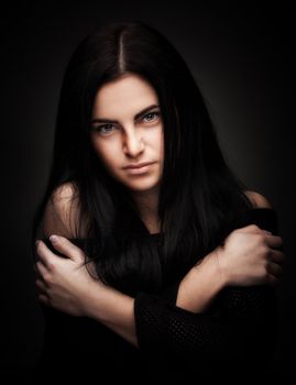 alluring woman in black dress posing over dark background