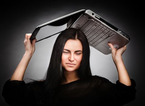 Stressed young woman with a laptop on her head