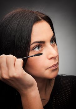 Woman applying mascara on her eyelashes
