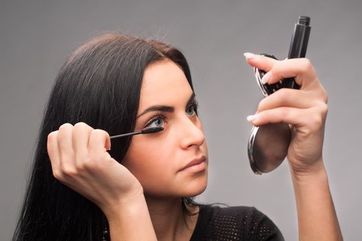 Woman applying mascara on her eyelashes