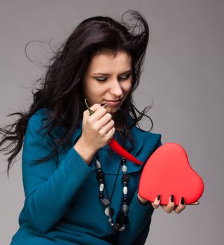 beautiful young woman hold in hand heart and red hot chili pepper